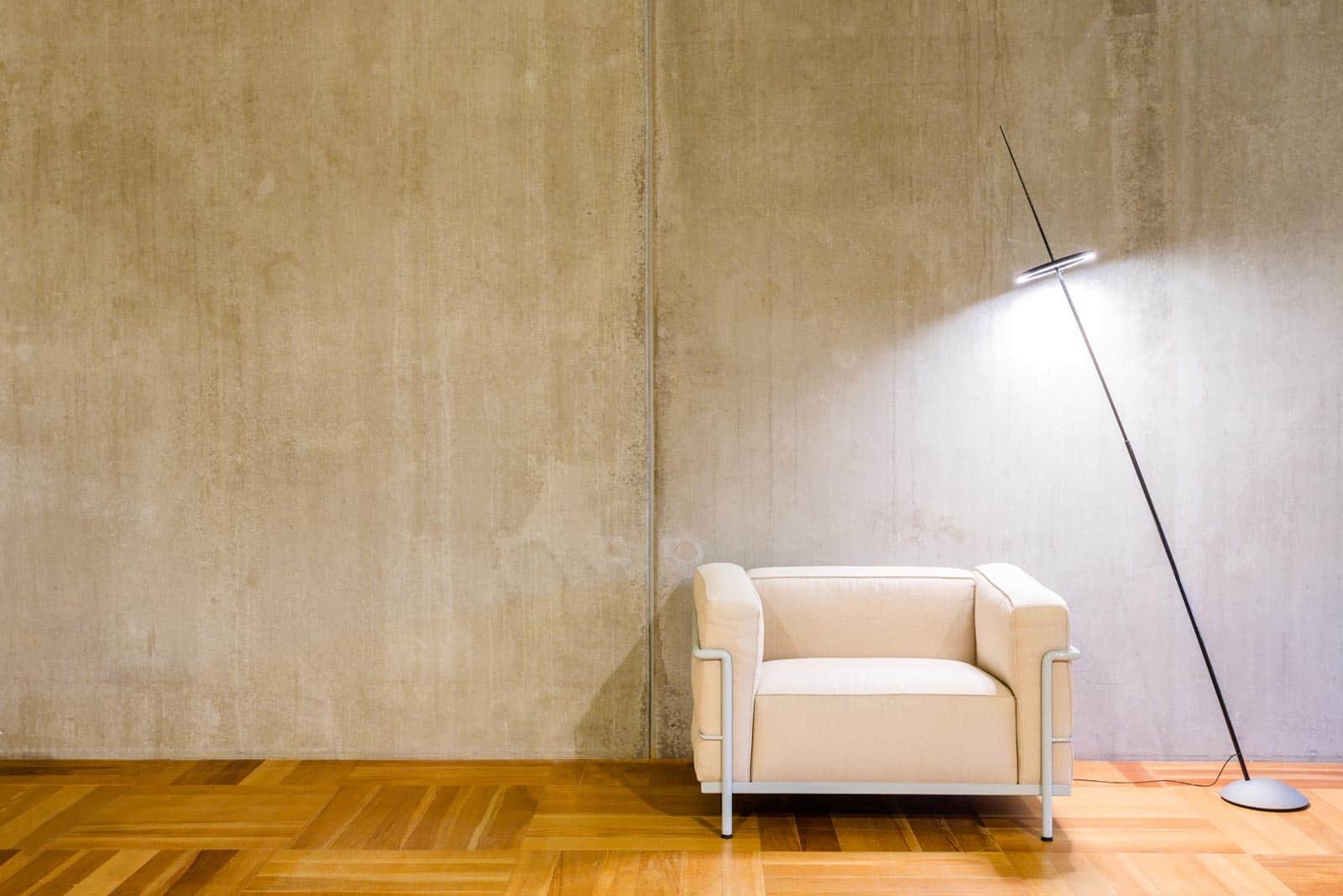 Betonnen wand met fauteuil en lamp