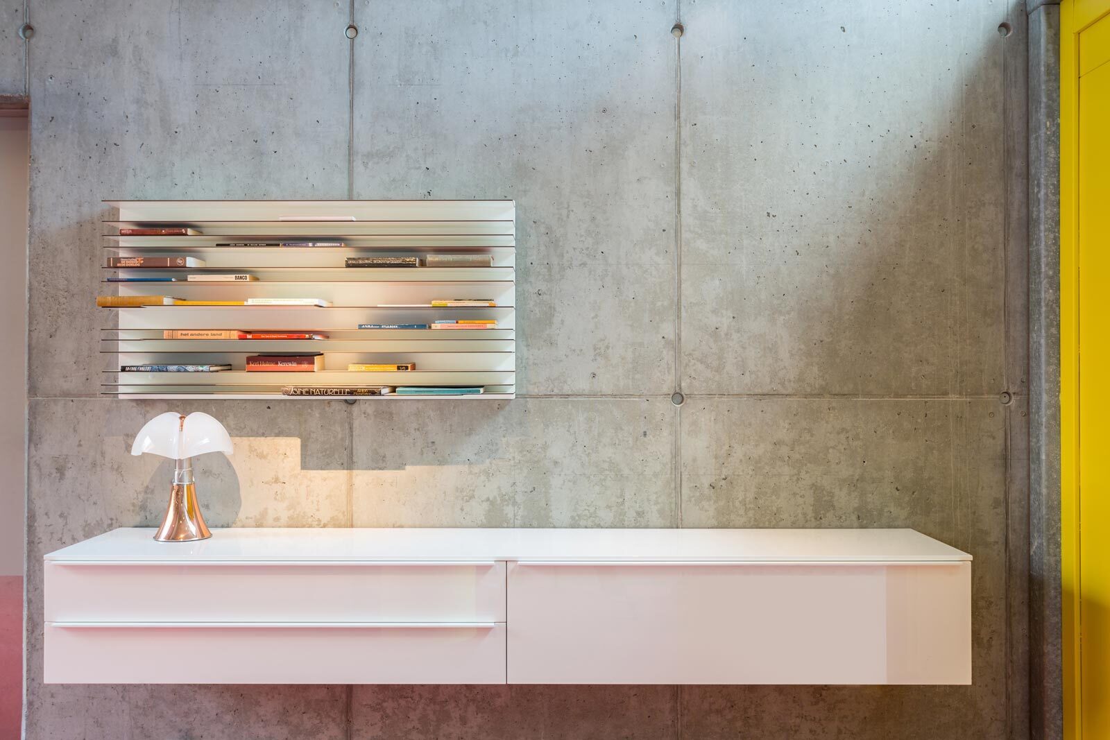 Betonnen wand met kastje en boekenplank