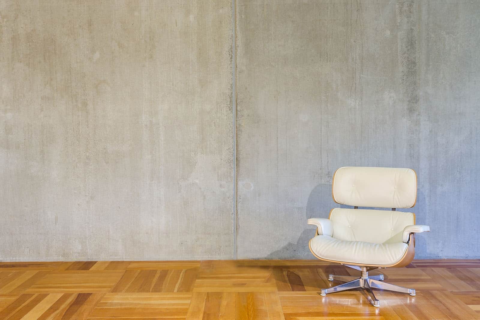 Betonnen wand met vloet en witte fauteuil