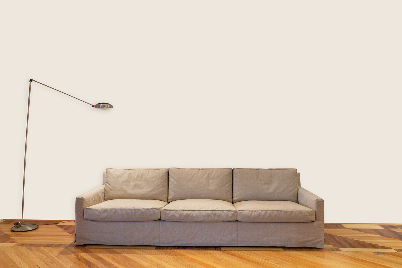 Witte wand met bruine bank en staande lamp L
