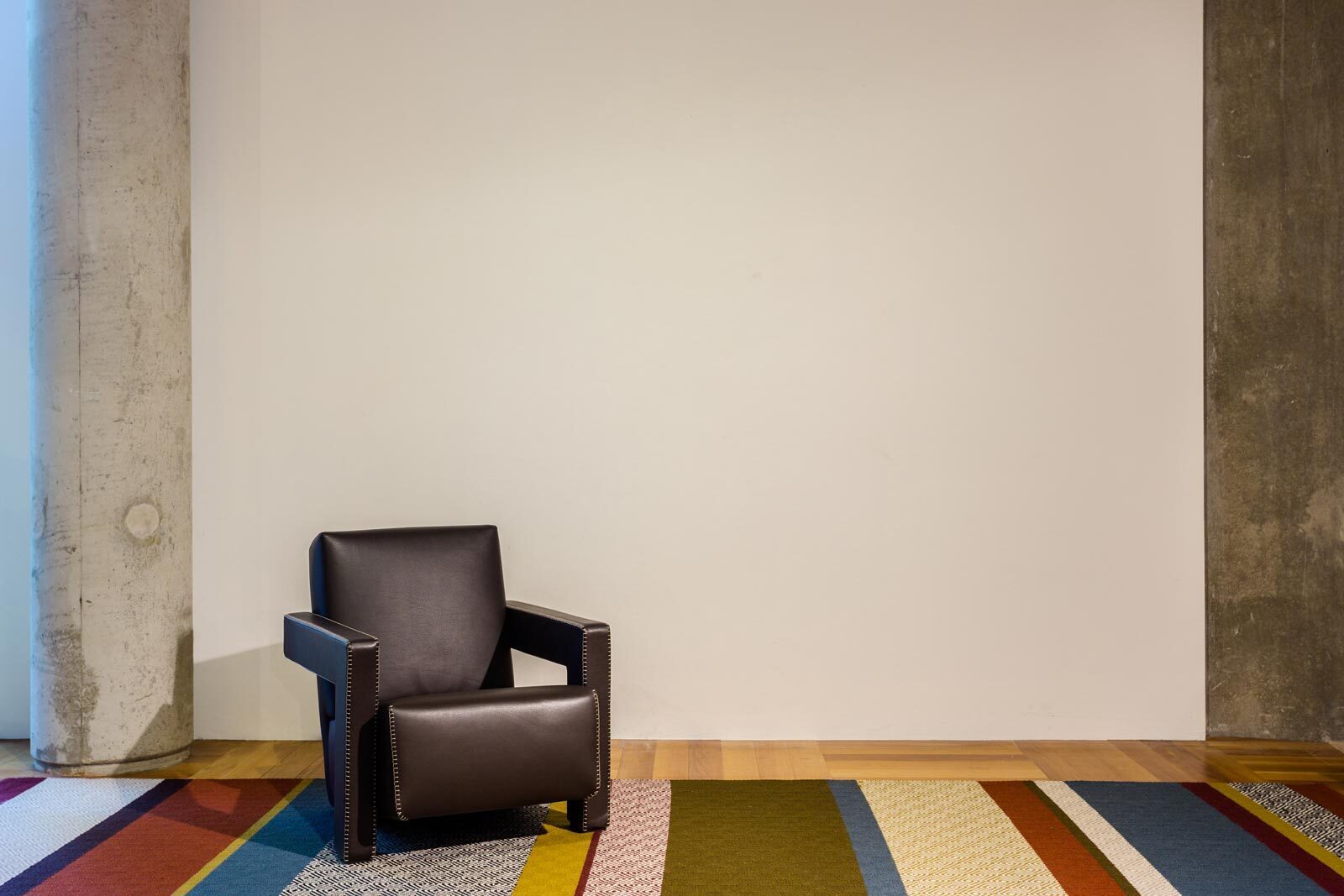 Witte wand met pilaar fauteuil en tapijt